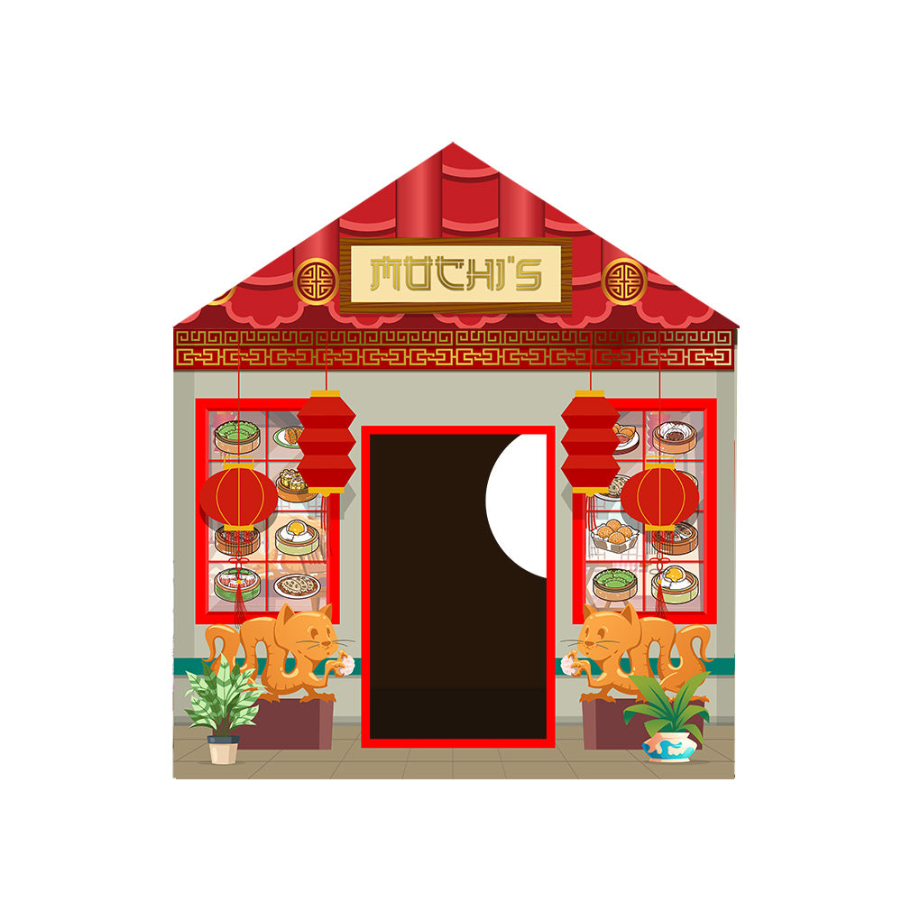 Front-facing cardboard cat house styled as a festive red-roofed shop with an Asian theme, decorated with illustrations of traditional figures and ornaments. The facade has a large doorway and a circular window opening