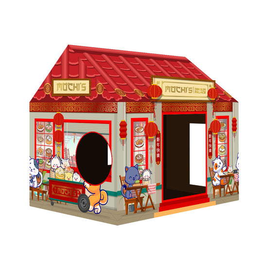 Angled view of a cardboard cat house designed like a traditional Asian-style shop with a red slanted roof, golden signboard, printed pillars, shelves of illustrated goods, and two entrances: a round cutout and a rectangular door.